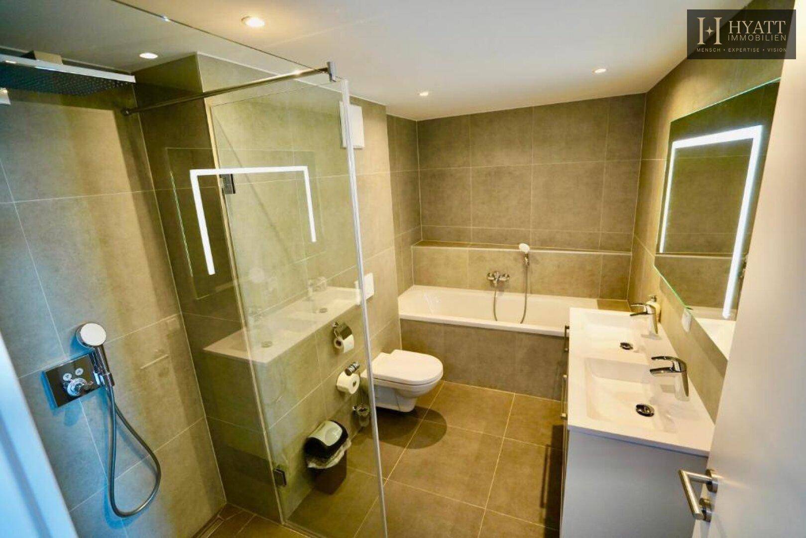 Modernes Badezimmer mit grauen Fliesen, Doppelwaschbecken, Badewanne und begehbarer Dusche.
