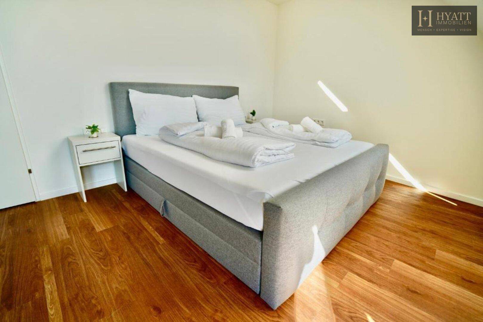 Helles Schlafzimmer mit bequemem Doppelbett, Holzboden und minimalistischer Einrichtung.