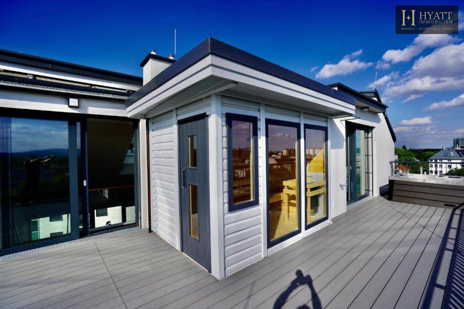 Großzügige Dachterrasse mit kleiner Hütte, Whirlpool und weitem Blick über die Stadt.