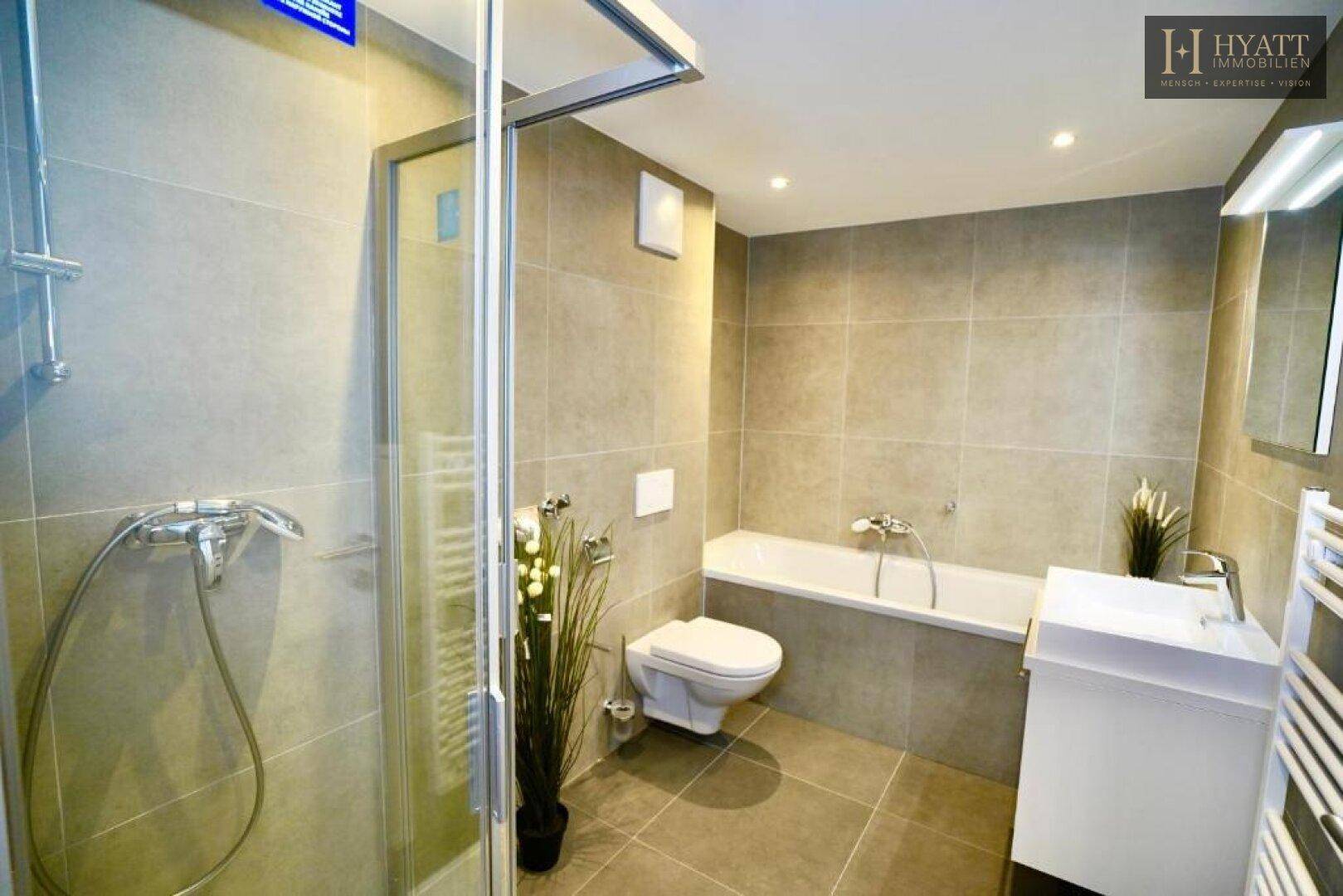 Modernes Badezimmer mit Dusche, Badewanne, WC und beheiztem Handtuchhalter.