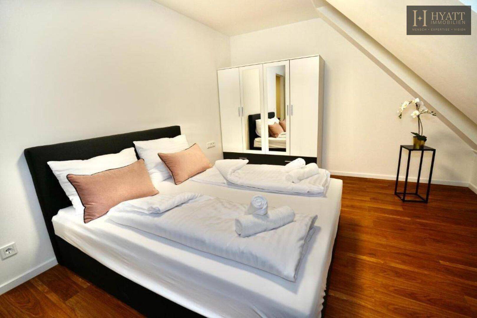 Gemütliches Schlafzimmer mit Doppelbett, Spiegelschrank und Dachschräge.