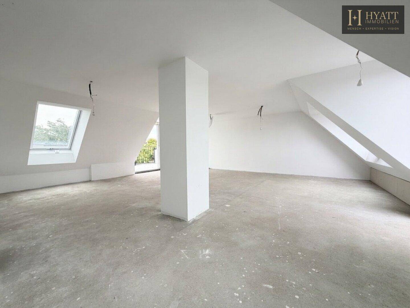 Geräumiger, unmöblierter Raum mit Betonboden, Dachschräge und Säule.