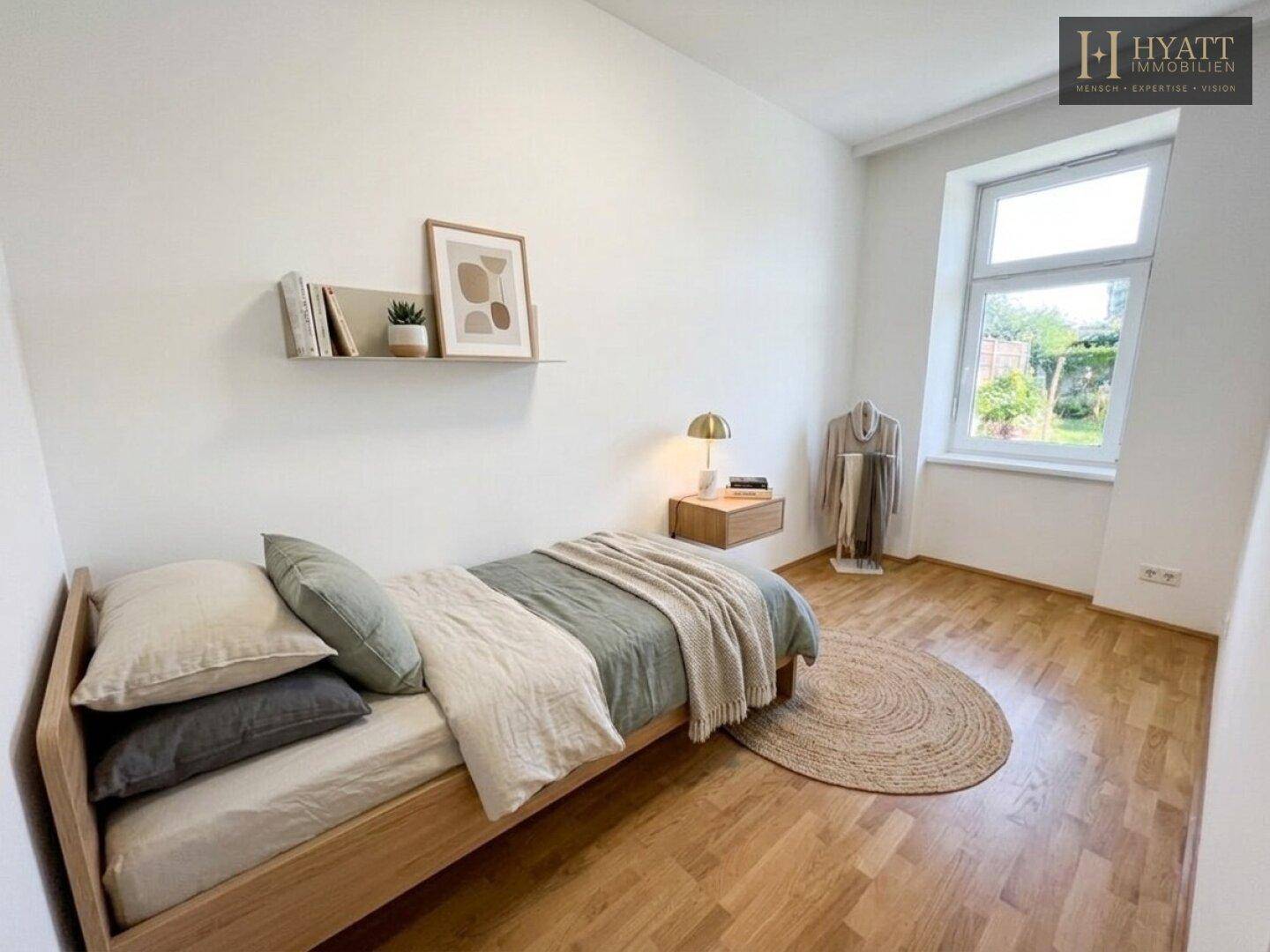Gemütliches Schlafzimmer mit Holzbett, Parkettboden und Blick ins Grüne durch das Fenster.