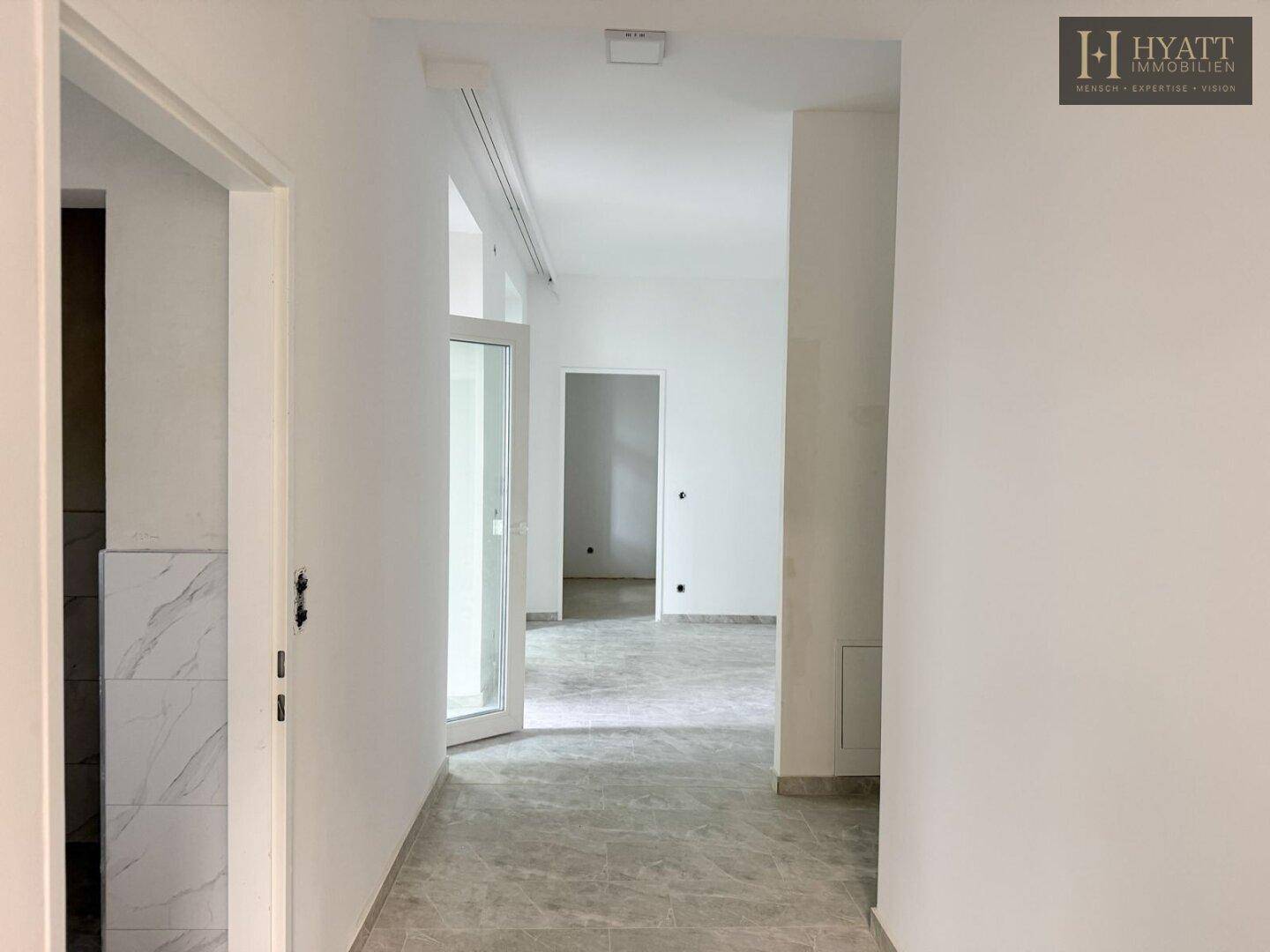 Heller Flur mit modernen Fliesen und Zugang zu weiteren Räumen der Wohnung.