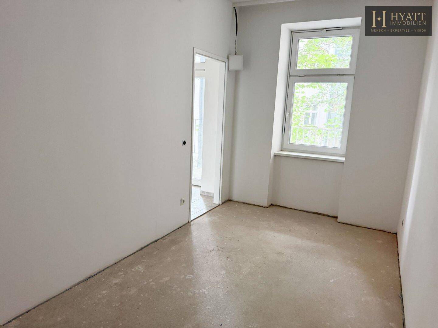 Leerer Raum mit Rohbetonboden und Fenster, bereit für die individuelle Raumgestaltung.
