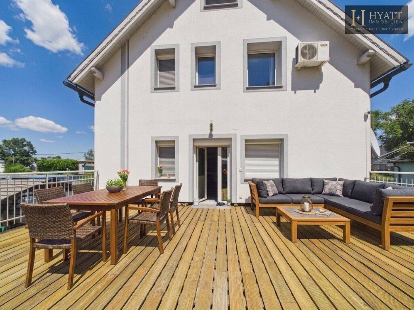 Große Holzterrasse mit Essbereich und Lounge-Möbeln, ideal für Entspannung im Freien.