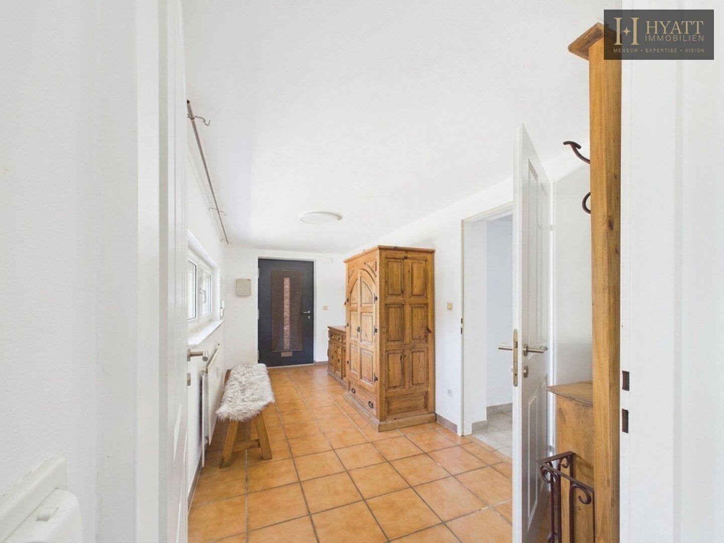 Geräumiger Eingangsbereich mit Terrakotta-Fliesen, Holzschrank und Garderobe.