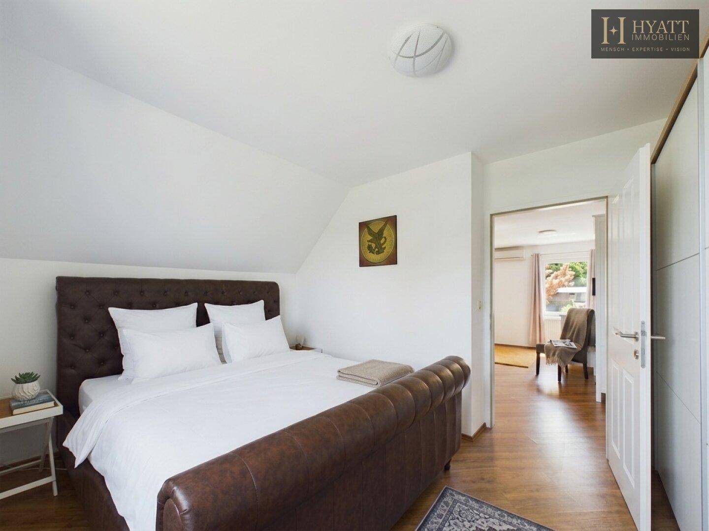 Gemütliches Schlafzimmer mit großem Doppelbett, Holzboden und Dachschräge.