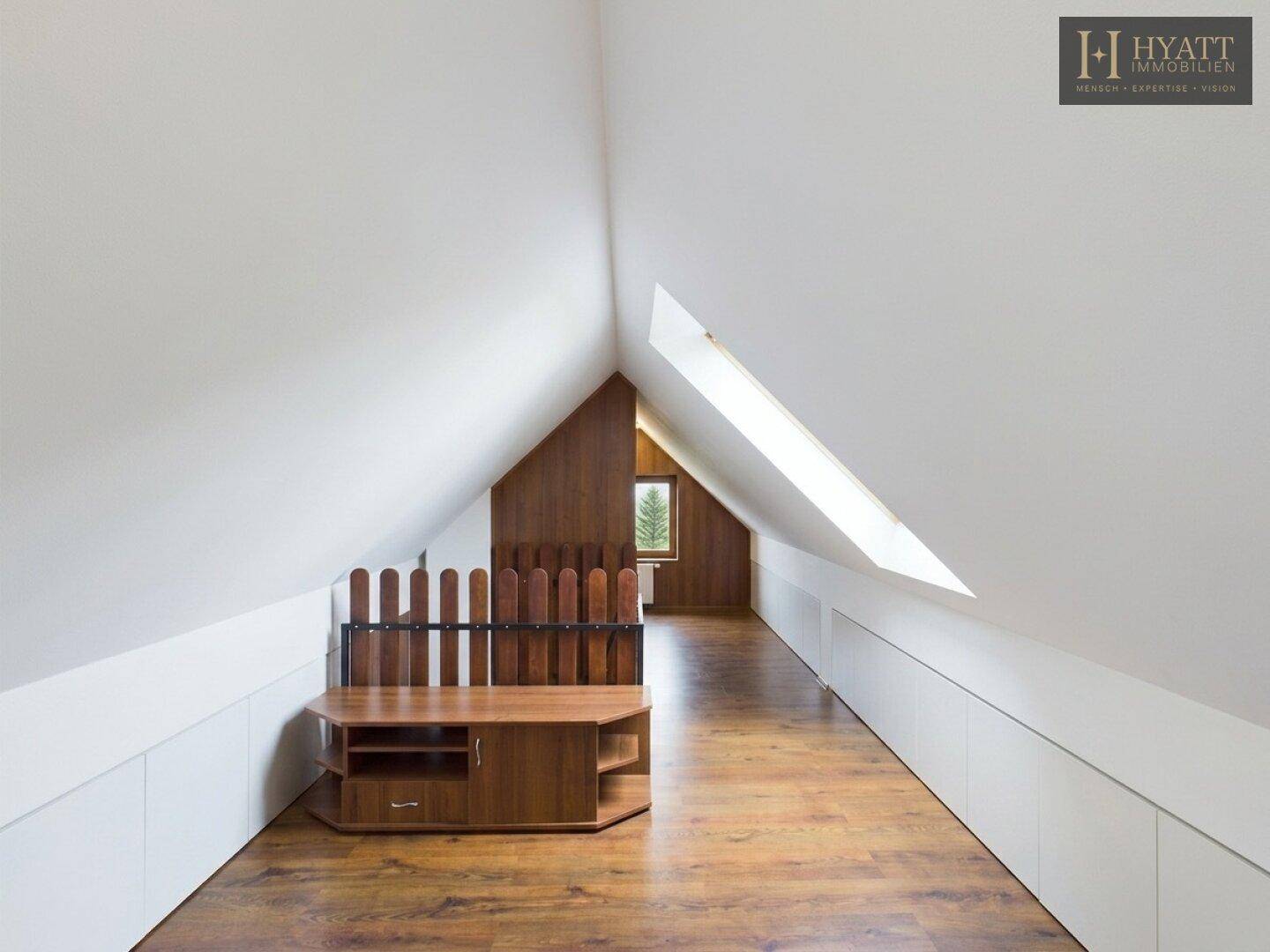 Ausgebauter Dachboden mit Holzboden, Dachschrägen und Stauraum.