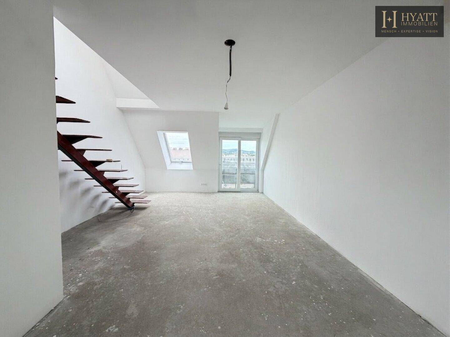 Unmöblierter Wohnbereich im Rohbau mit Dachschrägen, Treppe und Dachfenstern.