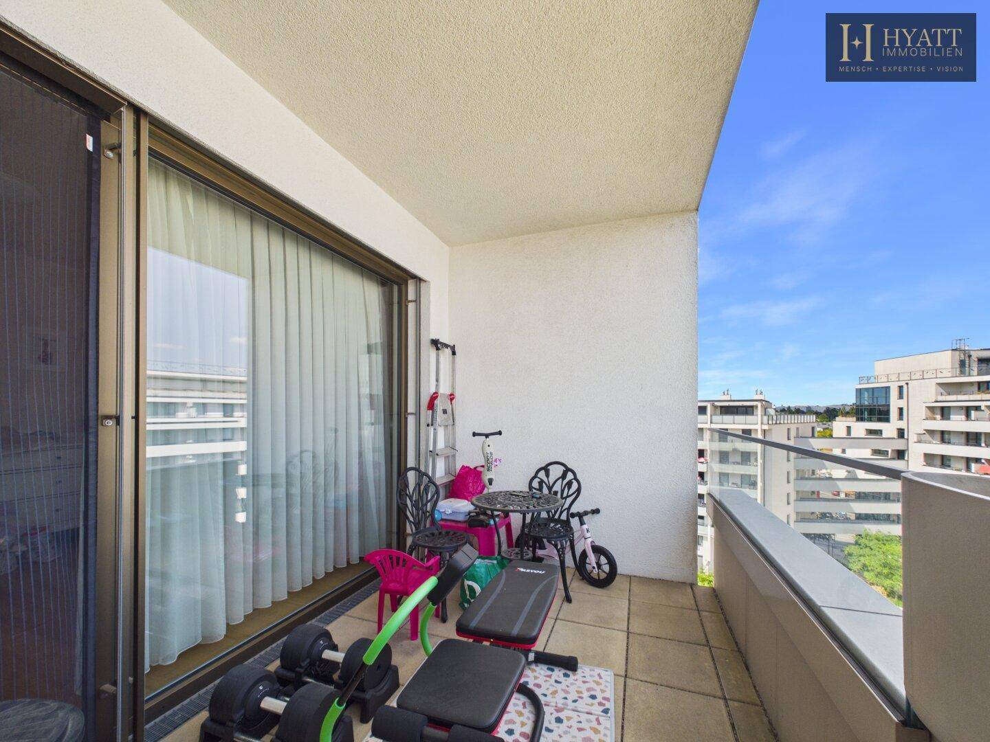 Kleiner Balkon mit Fitnessgeräten und Kinderspielzeug, bietet einen Blick auf die Umgebung.