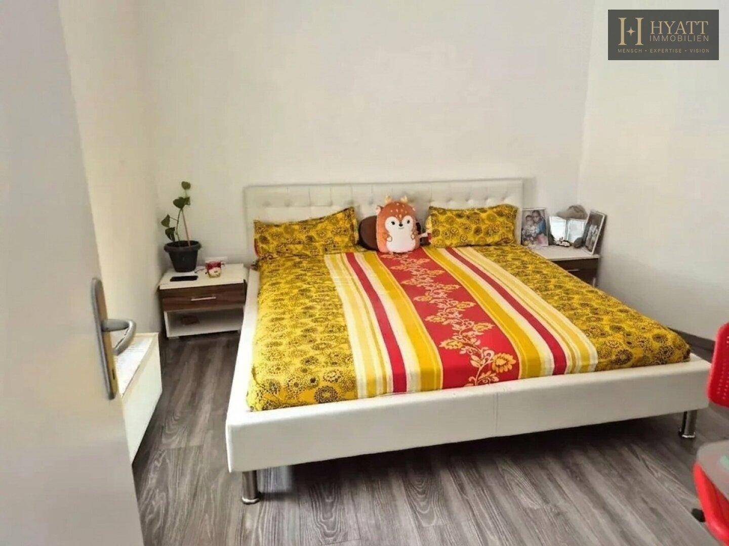 Helles Schlafzimmer mit weißem Bett, farbenfroher Bettwäsche und Nachttischen.