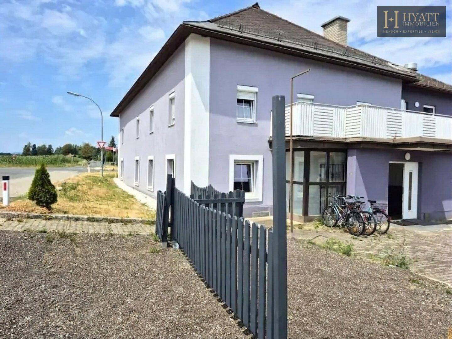 Außenansicht des lila Gebäudes mit geparkten Fahrrädern vor dem Eingang und einem Zaun.