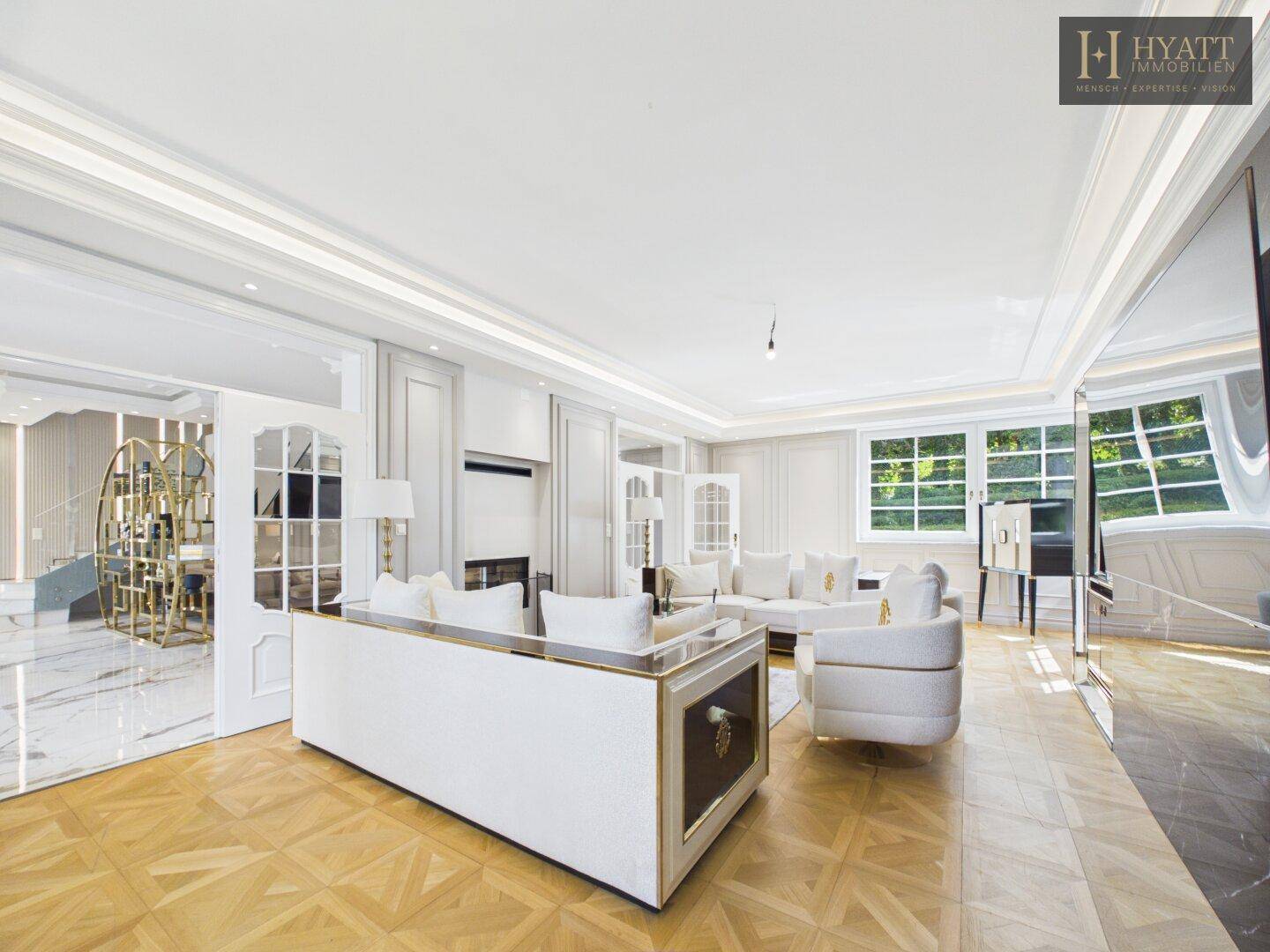 Elegantes Wohnzimmer mit Parkettboden, weißen Sofas und klassischer Wandgestaltung.