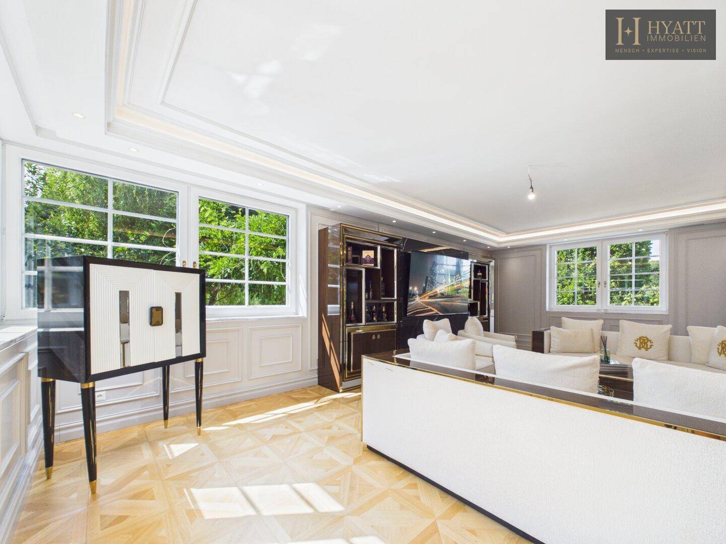Helles Wohnzimmer mit Parkettboden, großen Fenstern und eleganten Möbeln.
