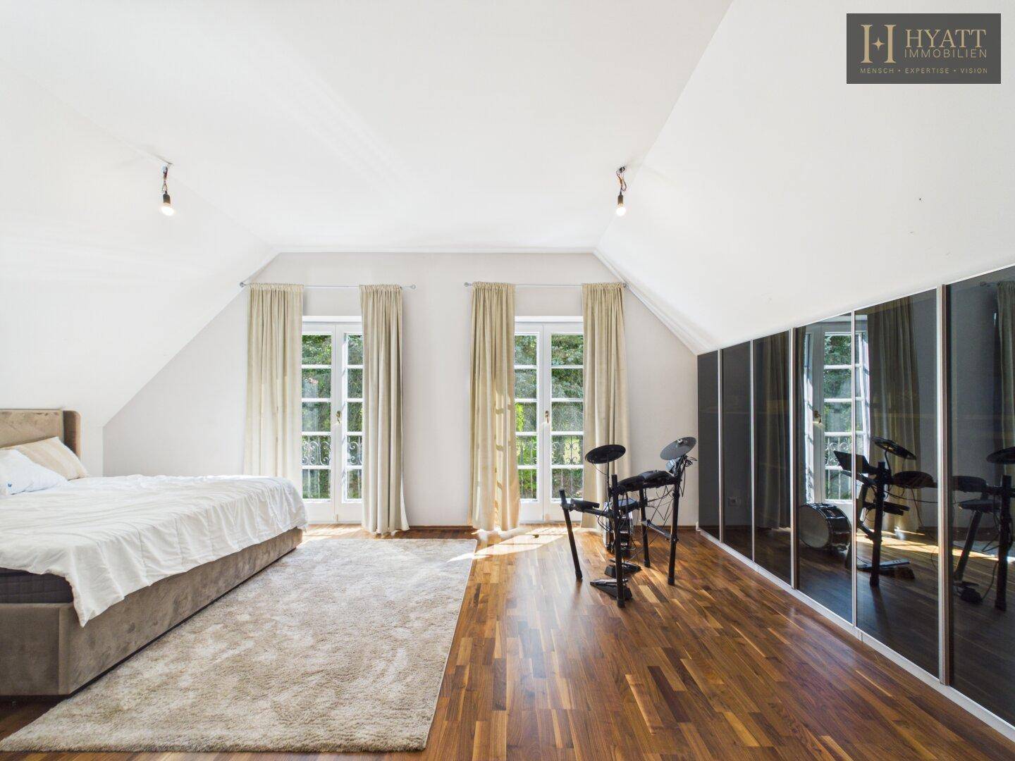 Geräumiges Schlafzimmer mit Holzboden, Einbauschränken und Zugang zum Balkon.