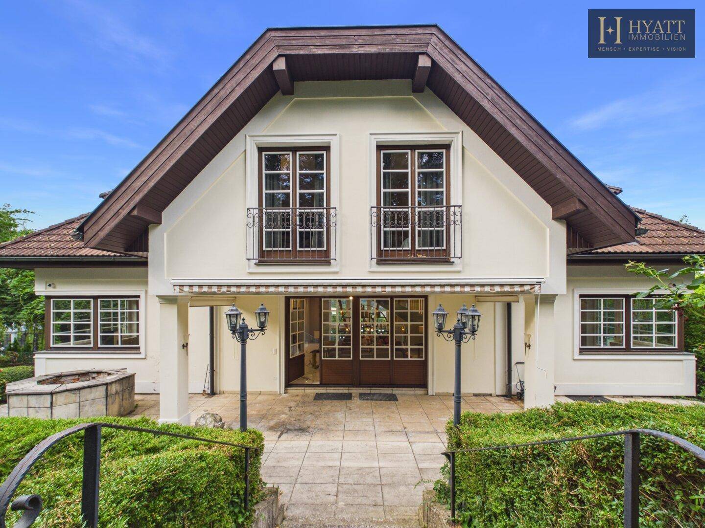Vorderansicht eines gepflegten Hauses mit klassischer Architektur, Satteldach und kleinen französischen Balkonen.