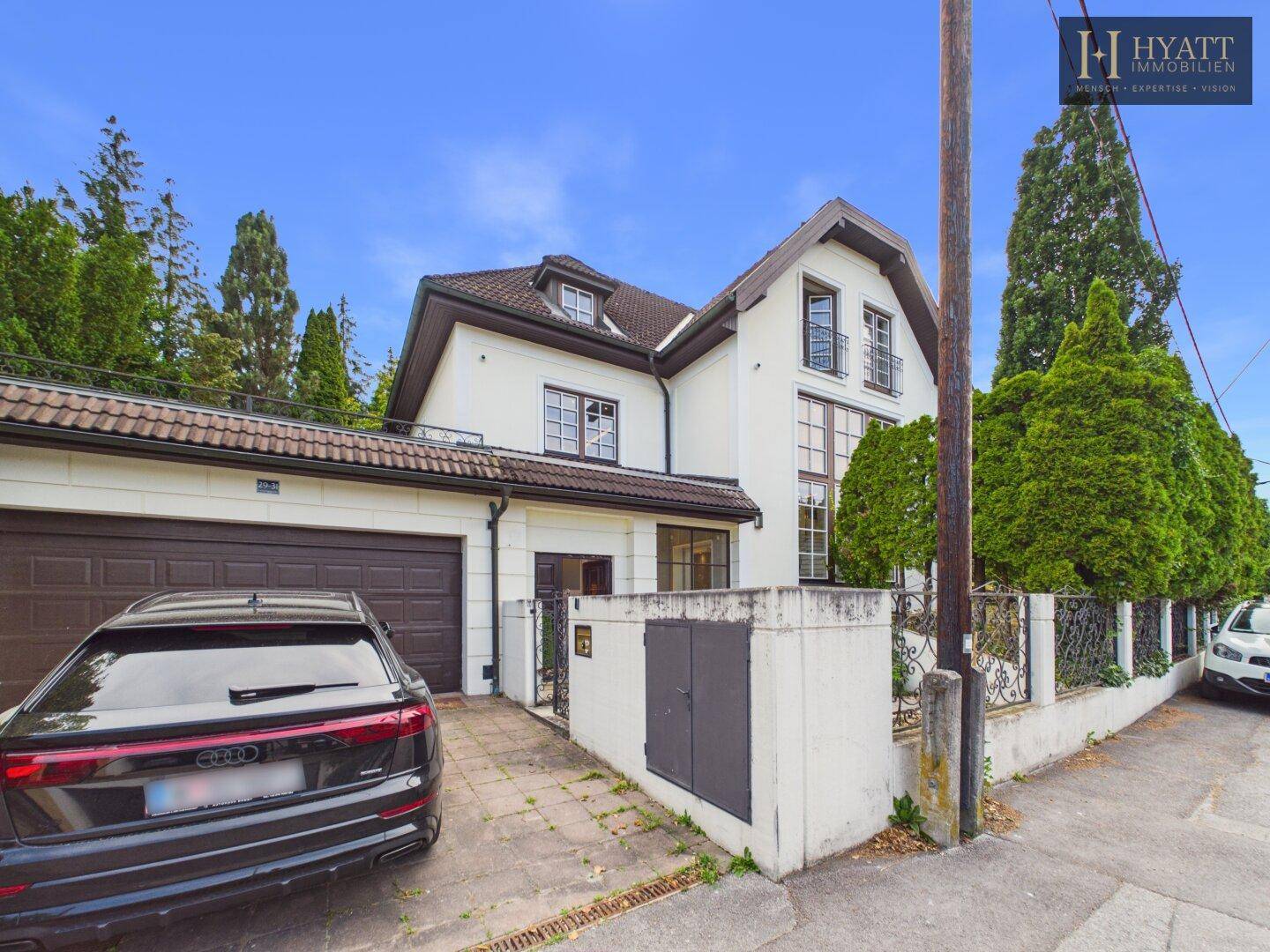 Ansicht des Hauses von der Straße mit integrierter Garage und gepflasterter Auffahrt.