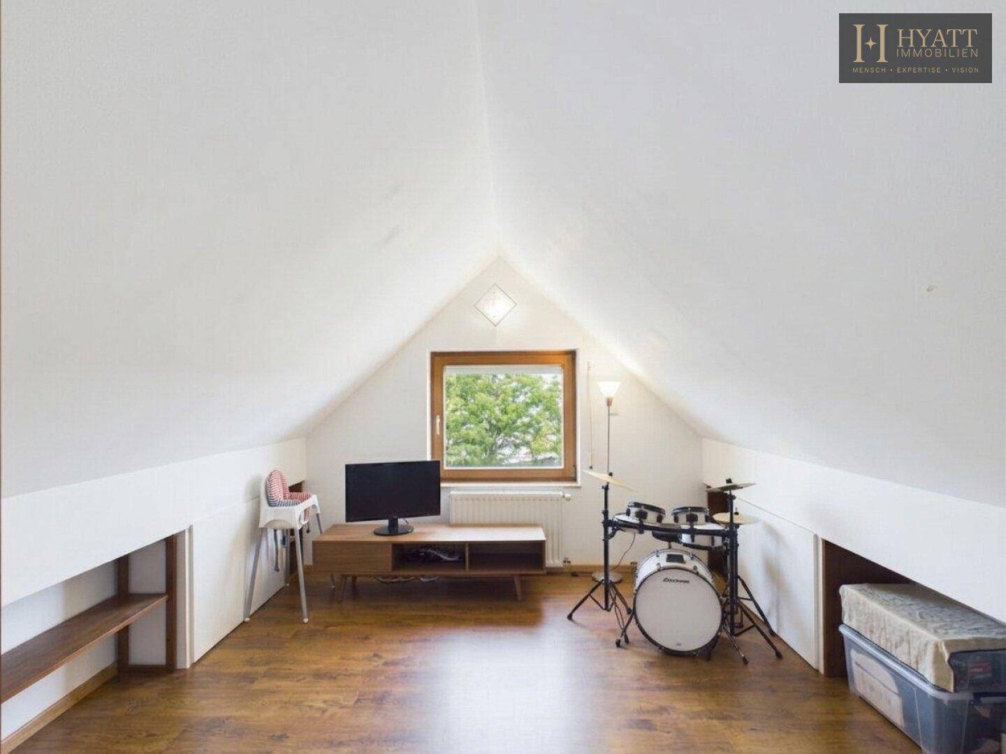 Dachgeschosszimmer mit Fenster, Schlagzeug und Fernseher, ideal als Hobby- oder Jugendzimmer.