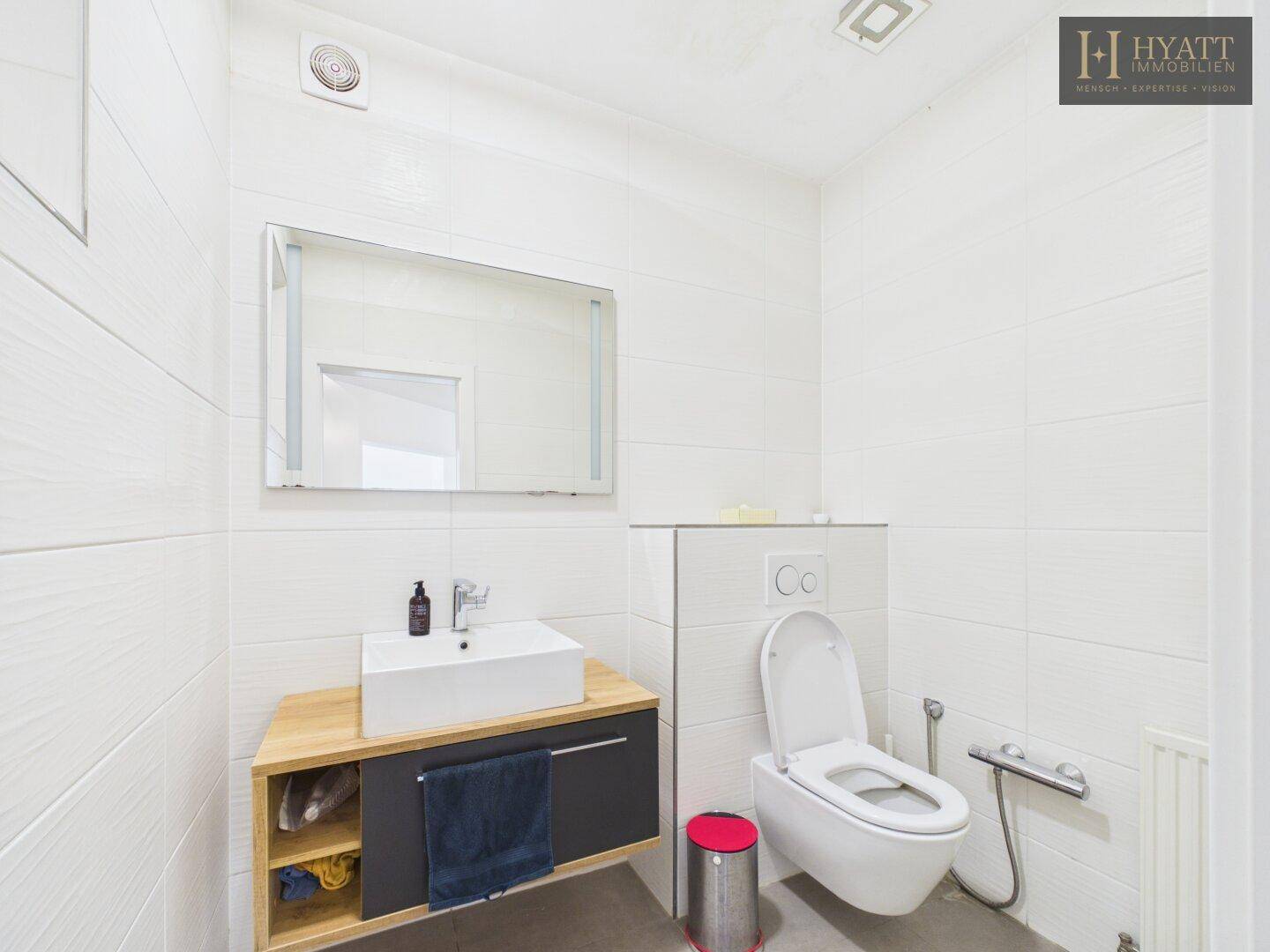 Modernes Gäste-WC mit wandhängendem WC, Waschbecken und weißen Fliesen.