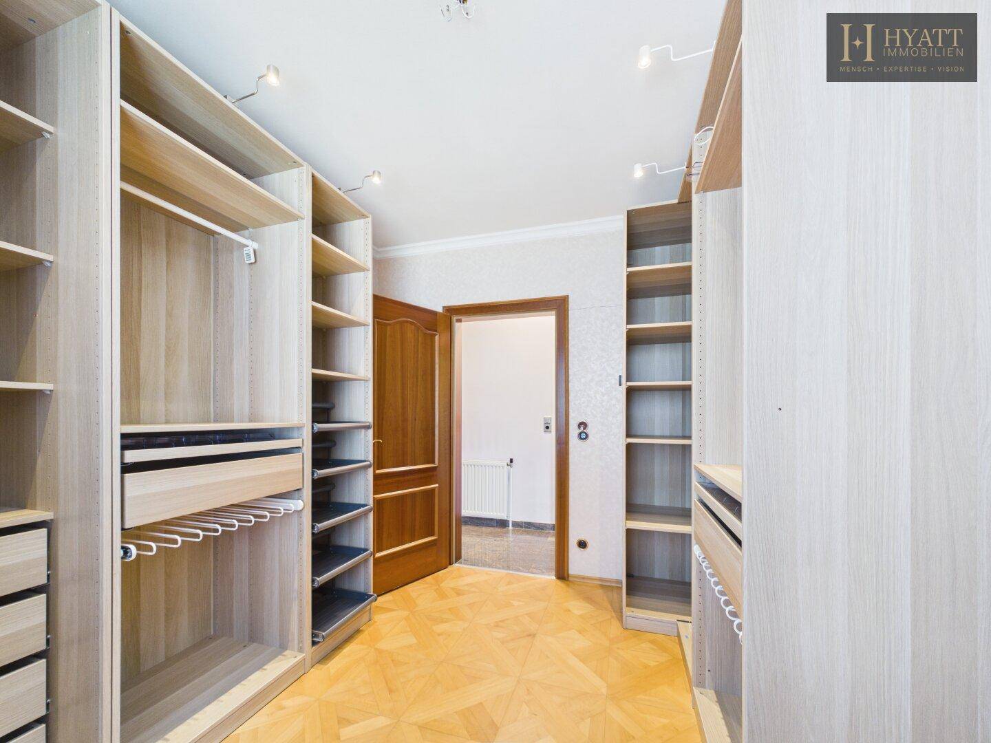 Geräumiger begehbarer Kleiderschrank mit vielen offenen Regalen und Holzboden.