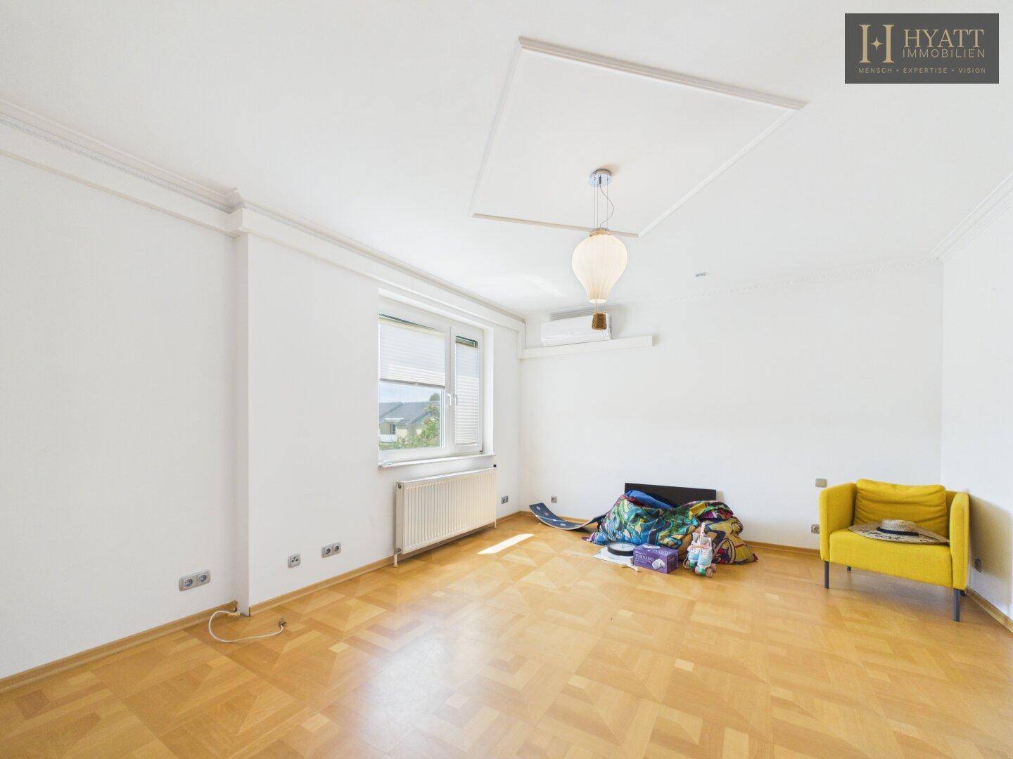 Helles Wohnzimmer mit Holzboden, weiß gestrichenen Wänden und einem Fenster.