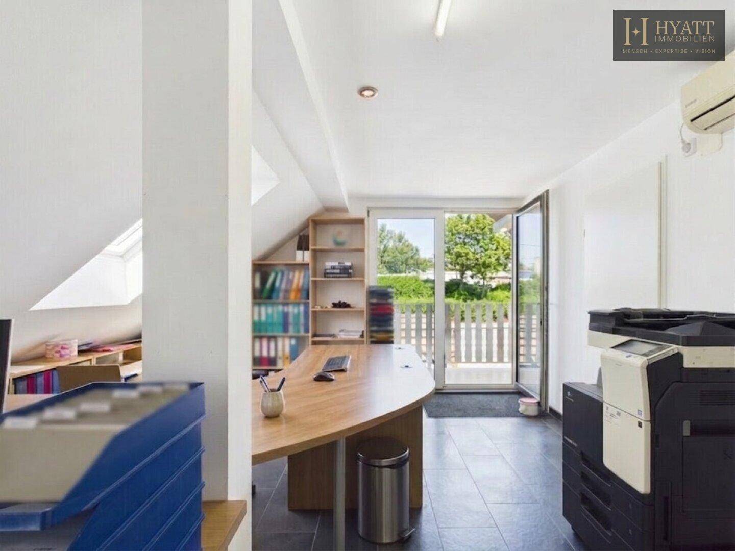 Helles Dachgeschossbüro mit Schreibtisch, Drucker und Zugang zu einem Außenbereich mit Zaun.