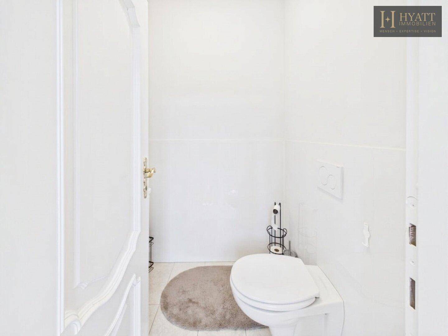 Helles Gäste-WC mit weiß gefliesten Wänden und einer modernen wandhängenden Toilette.