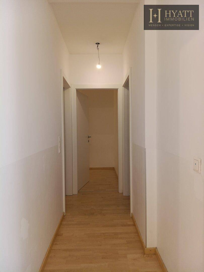 Langer, heller Flur mit Holzfußboden, der zu verschiedenen Zimmern der Wohnung führt.