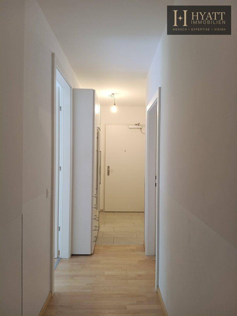 Heller Flur mit gemischtem Bodenbelag und einem Garderobenschrank, der zum Eingangsbereich führt.