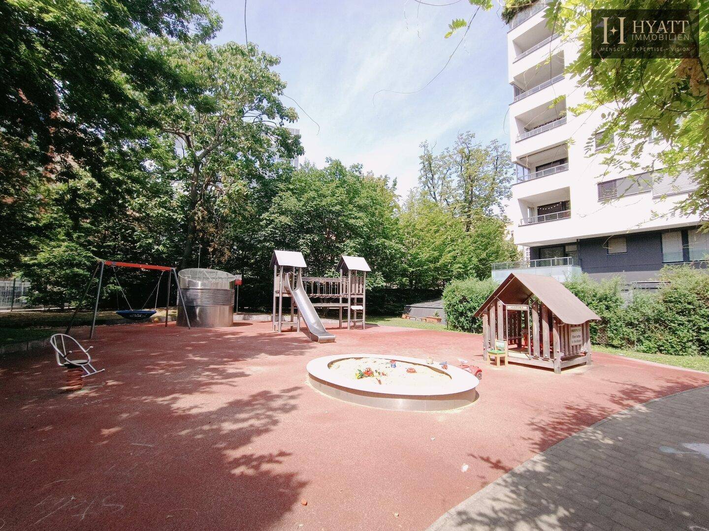 Kinderspielplatz mit Sandkasten, Rutsche und Schaukeln, direkt neben dem Wohngebäude.
