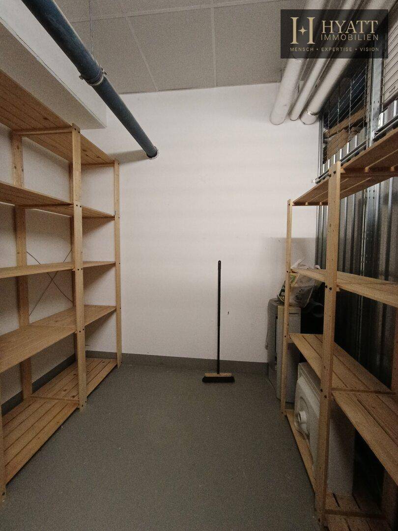 Geräumiger Abstellraum mit stabilen Holzregalen und sichtbaren Versorgungsleitungen.