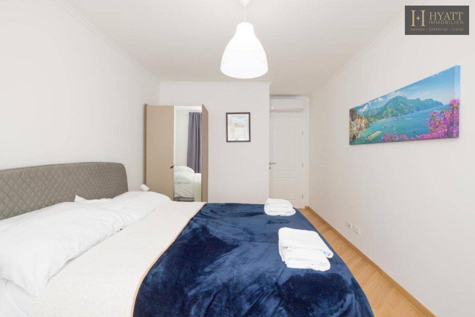 Gemütliches Schlafzimmer mit Doppelbett, Kleiderschrank und einem farbenfrohen Wandbild.