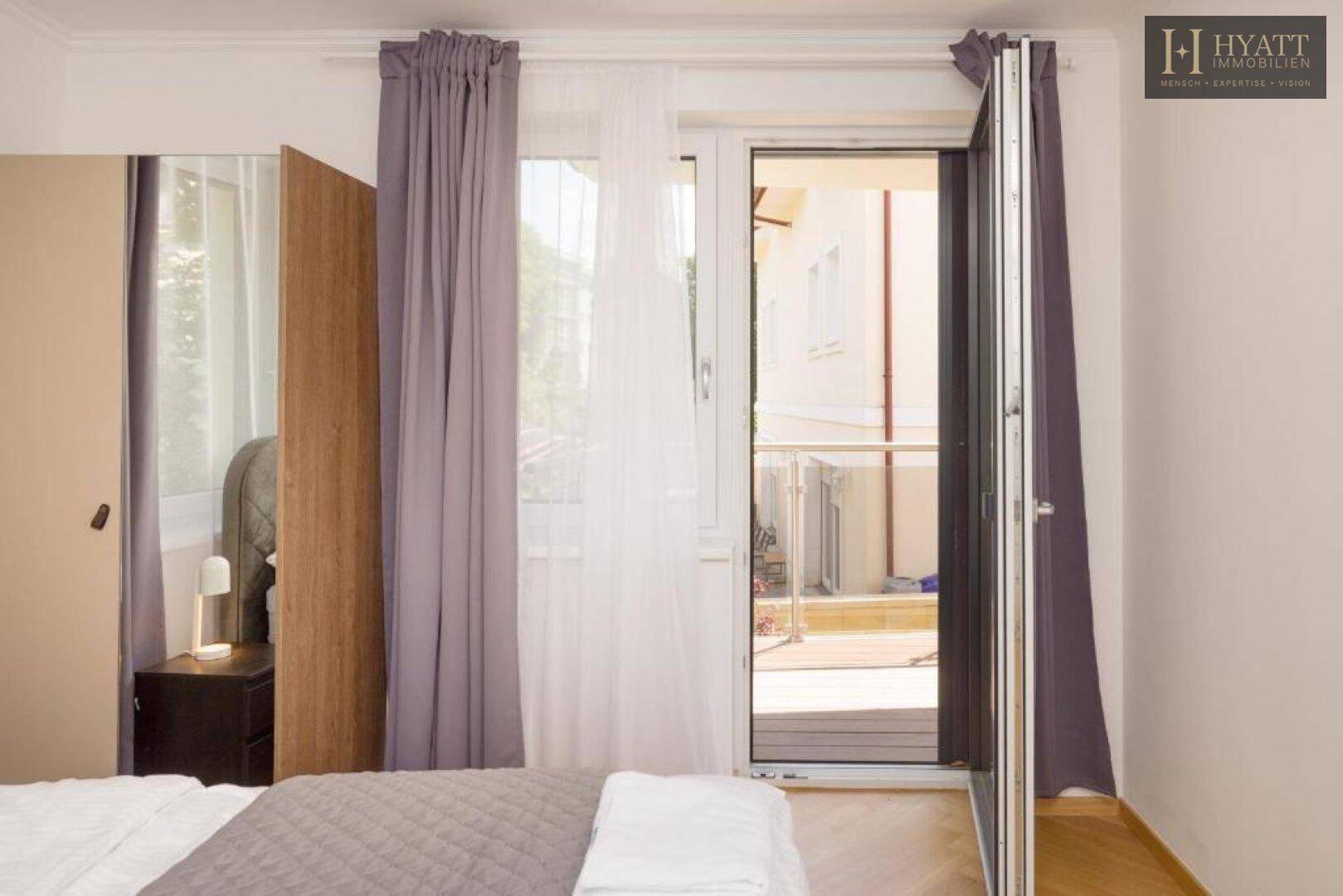 Schlafzimmer mit Zugang zu einem Außenbereich durch eine große Fenstertür.