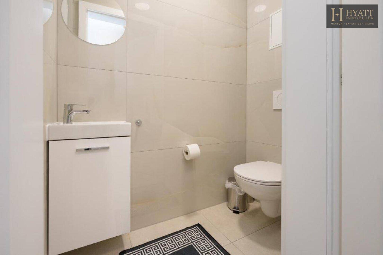 Helles Gäste-WC mit modernem Waschbecken und Toilette, gefliest in neutralen Tönen.