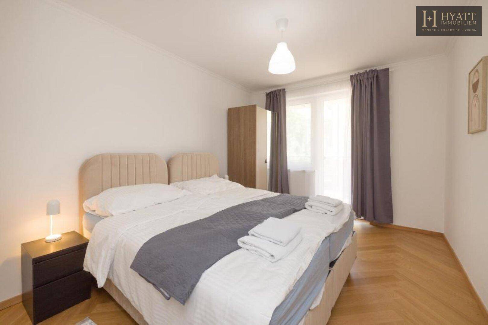 Komfortables Schlafzimmer mit Doppelbett, Nachttisch und hellem Fenster.