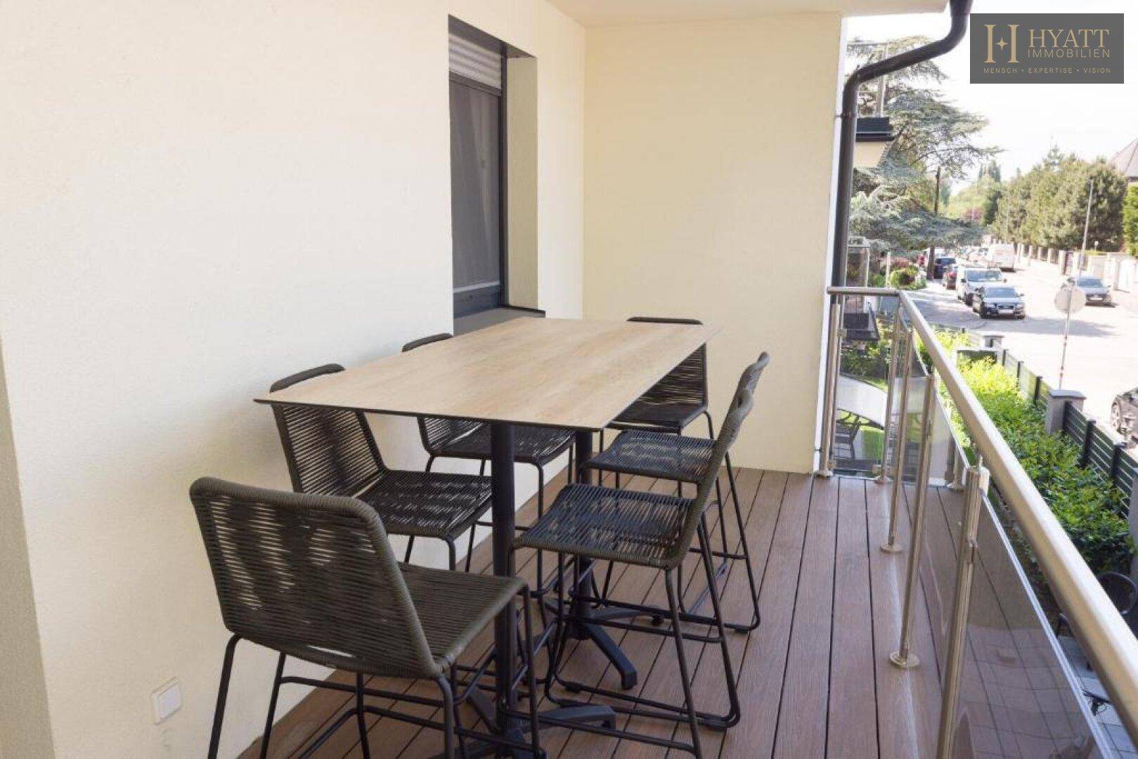 Balkon mit Esstisch und Stühlen, ideal für Mahlzeiten im Freien mit Blick auf die Straße.