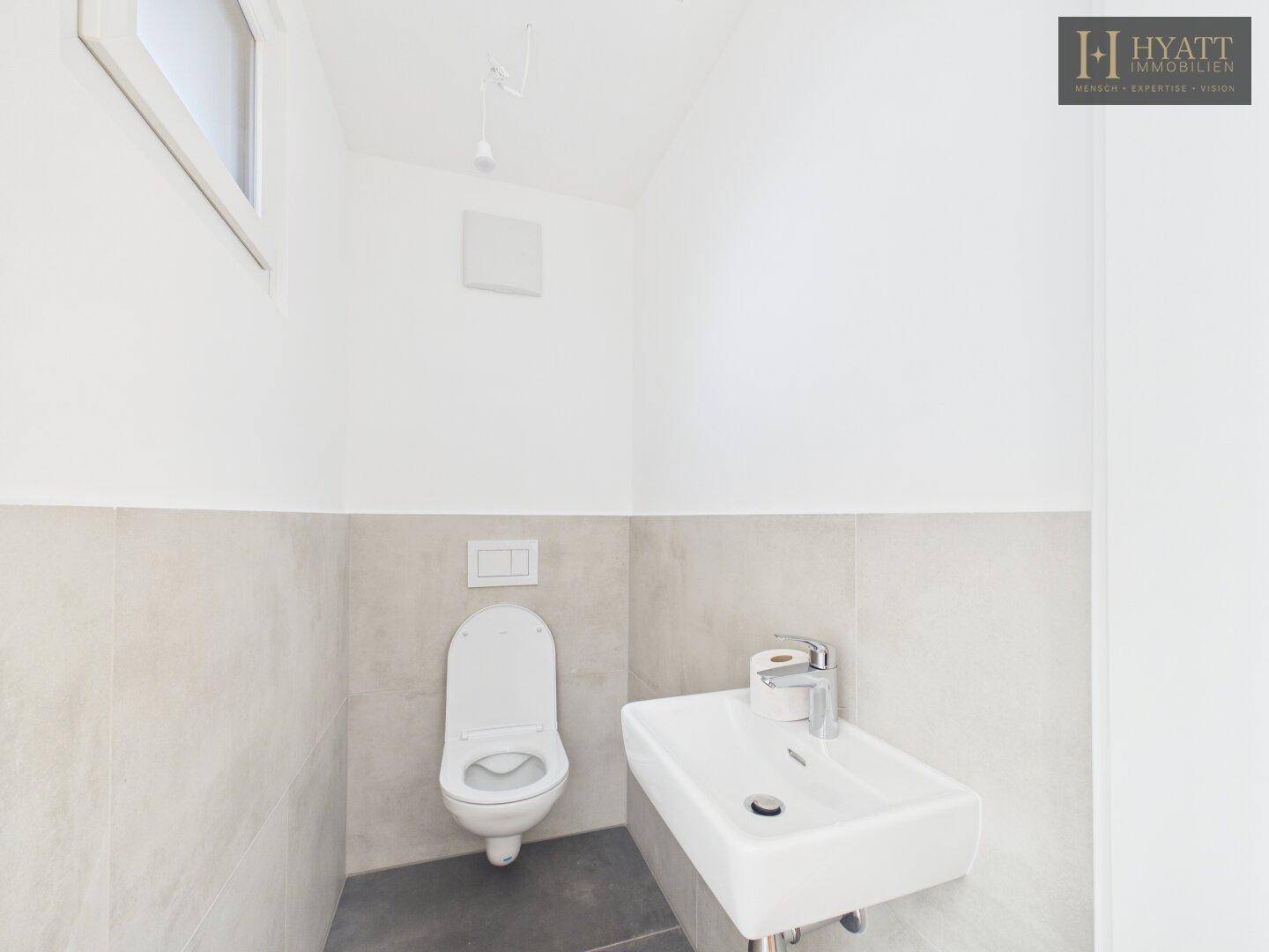 Gäste-WC mit Fenster, modernem Waschbecken und Wand-WC.