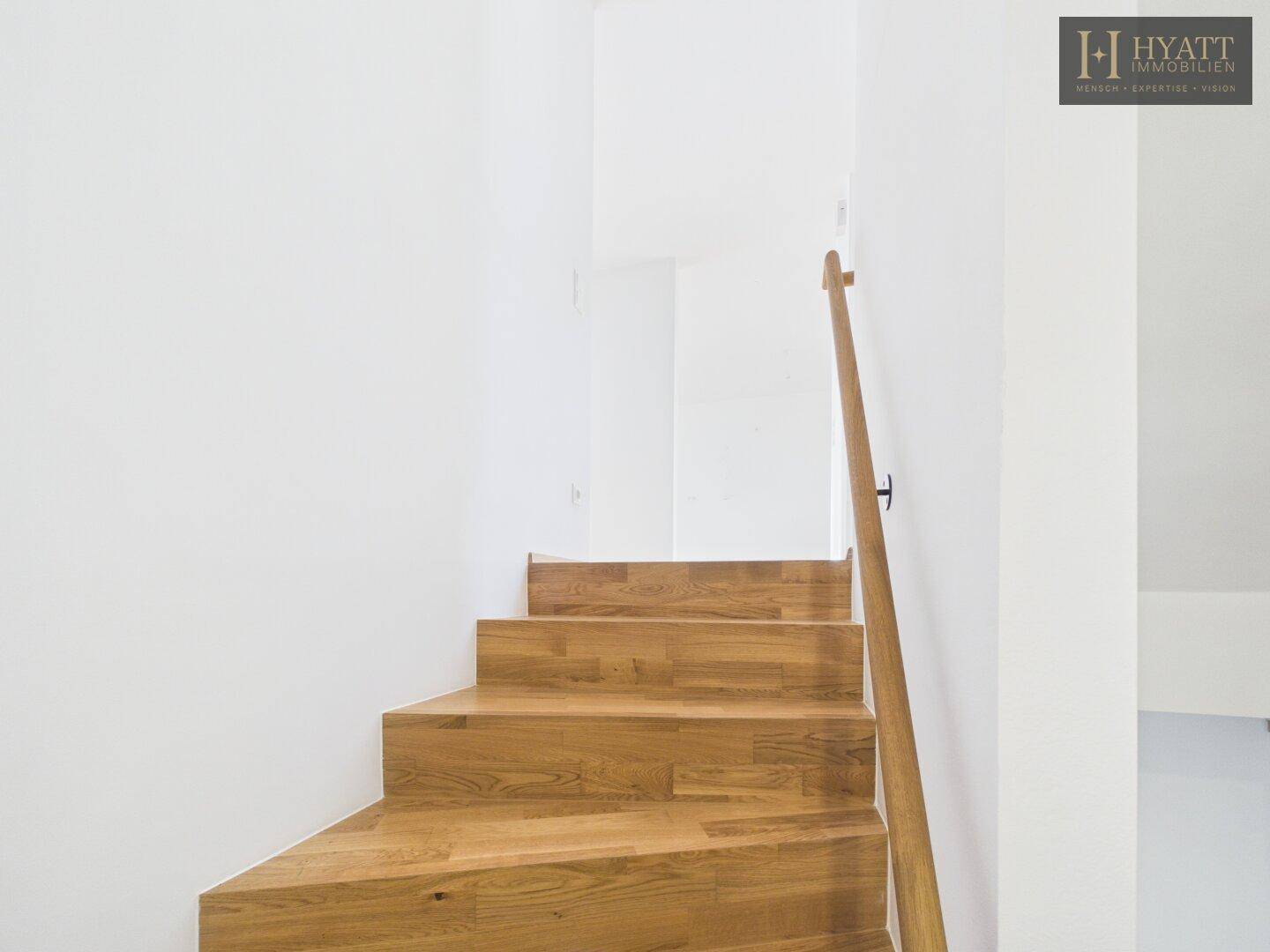 Detailansicht der Holztreppe mit passendem Handlauf in hellem Holz.