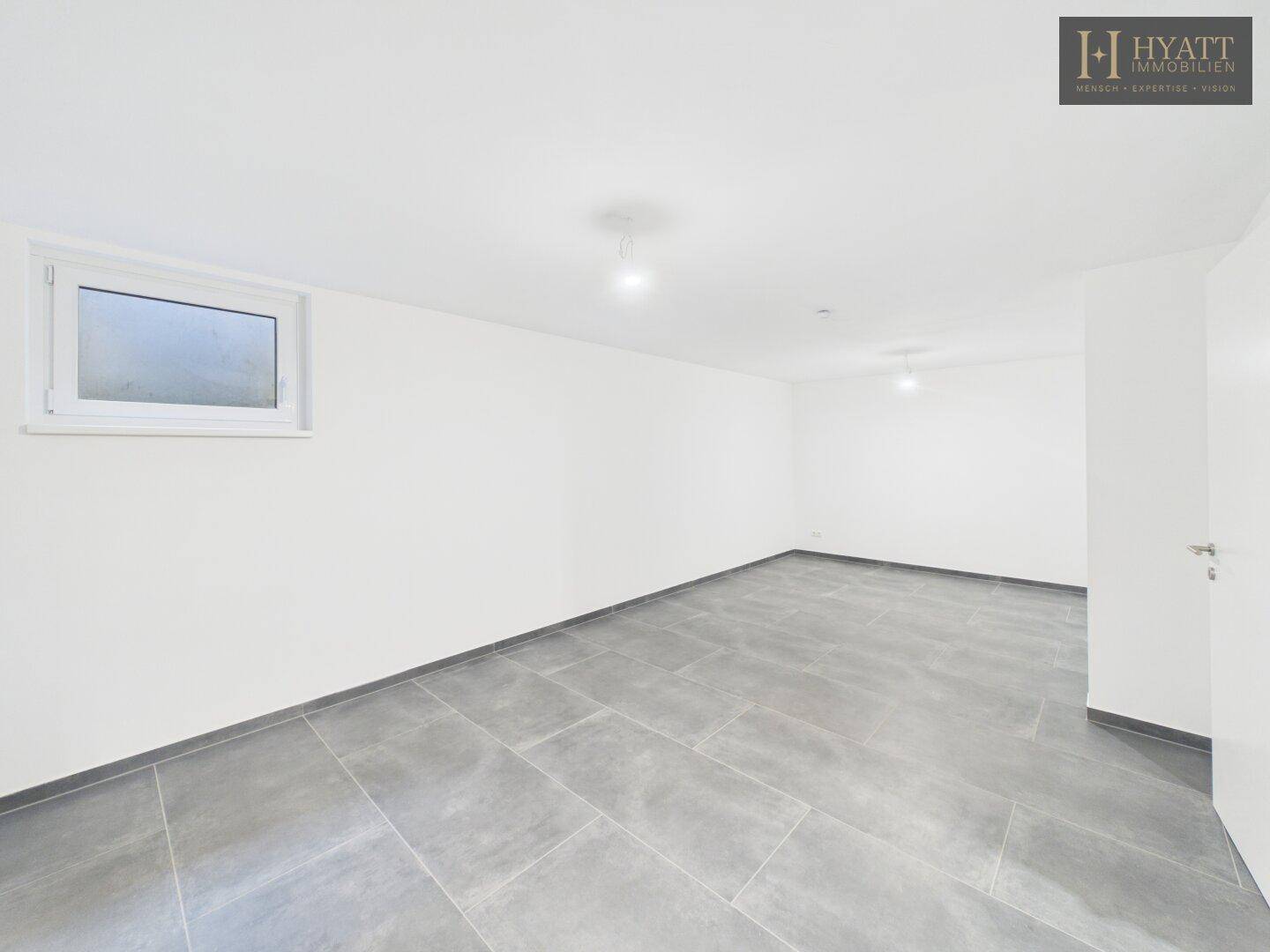 Geräumiger Kellerraum mit Fliesenboden und kleinem Fenster für Tageslicht.