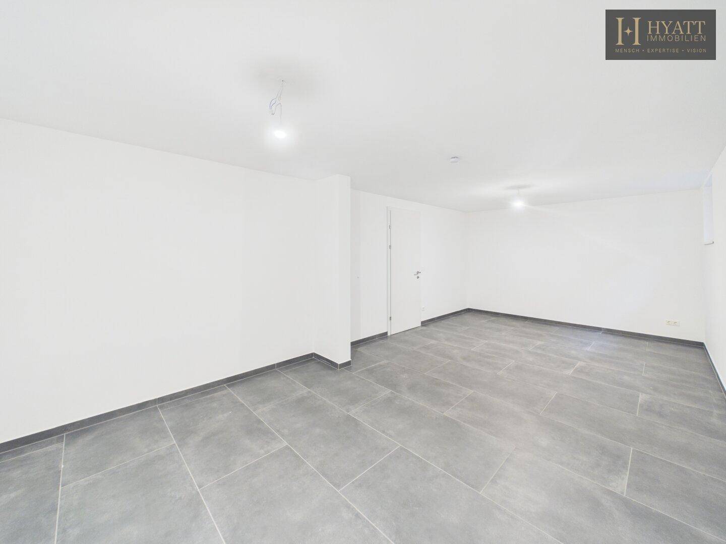 Heller Kellerraum mit modernem Fliesenboden und weiß gestrichenen Wänden.