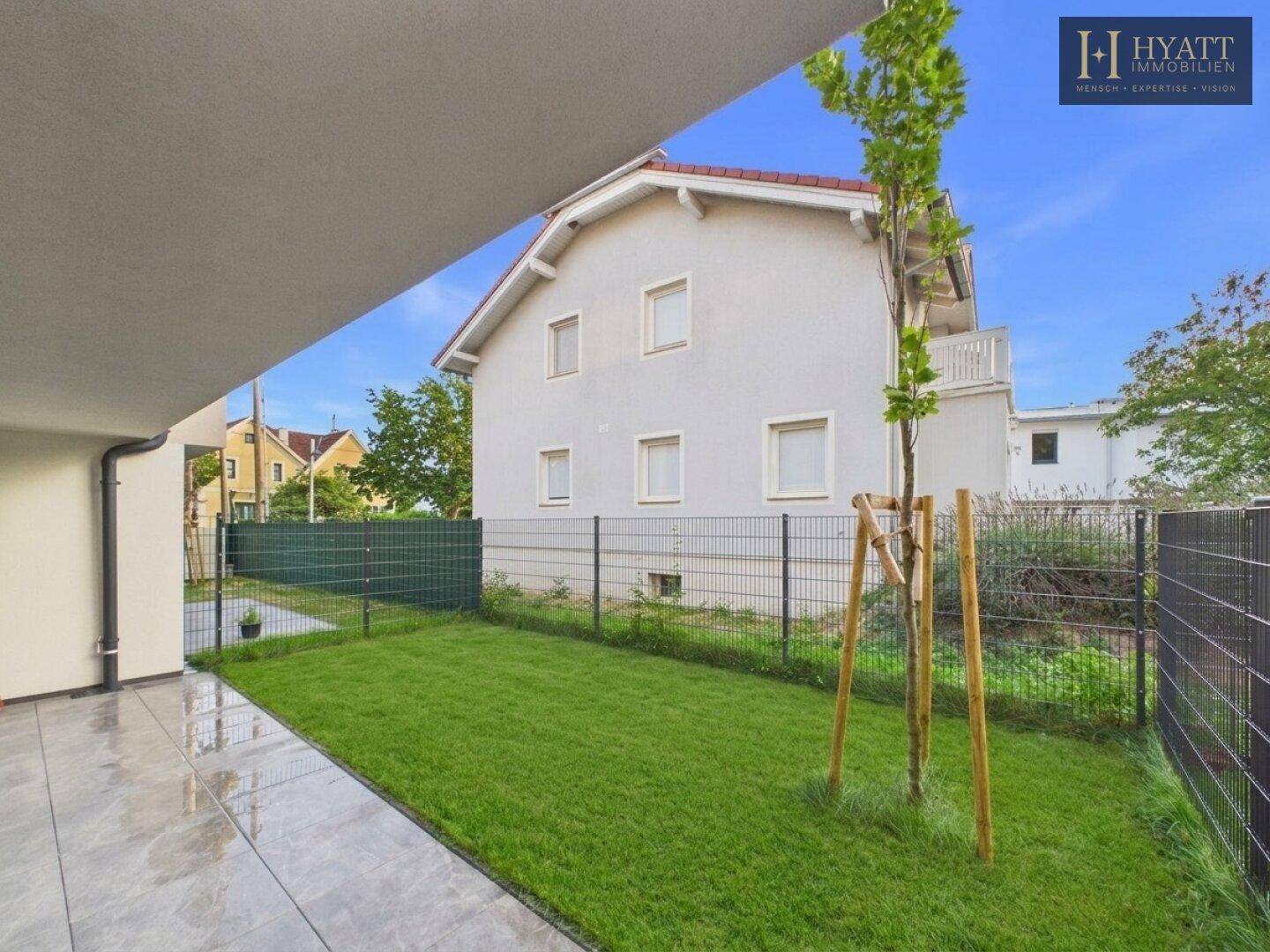 Kleiner, gepflegter Gartenbereich mit Rasenfläche und Blick auf benachbarte Gebäude.