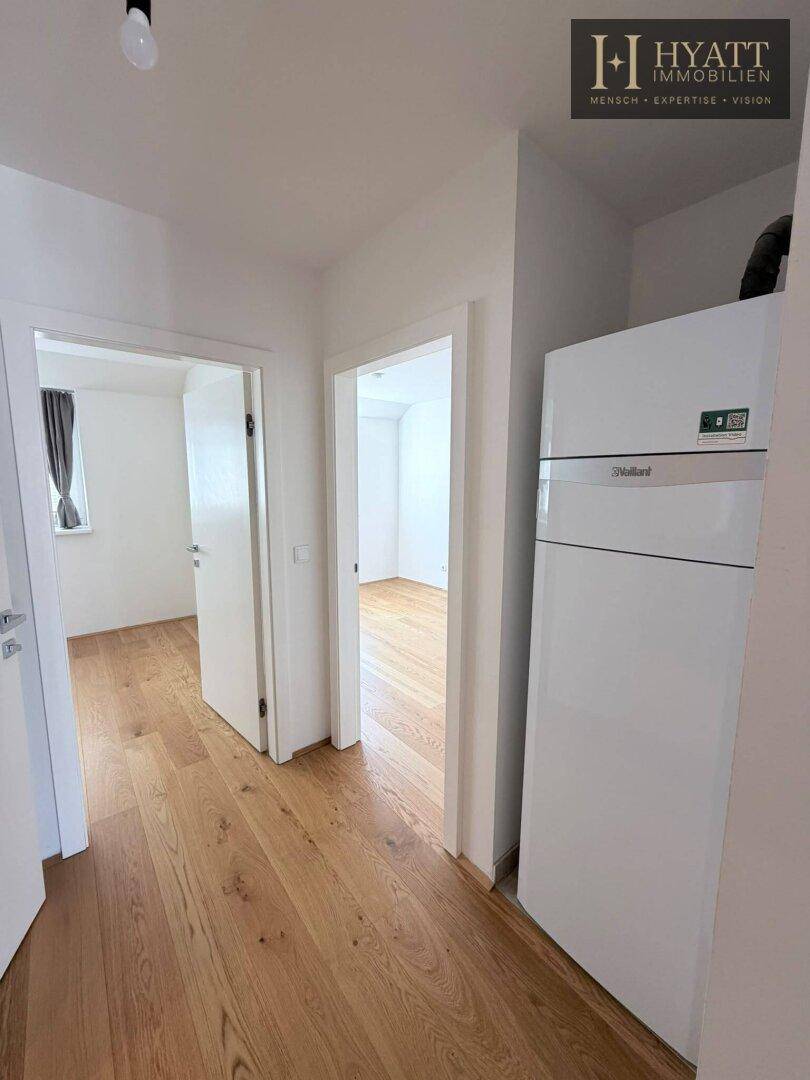 Heller Flur mit Holzboden und einem modernen Heizsystem, das zu weiteren Räumen führt.