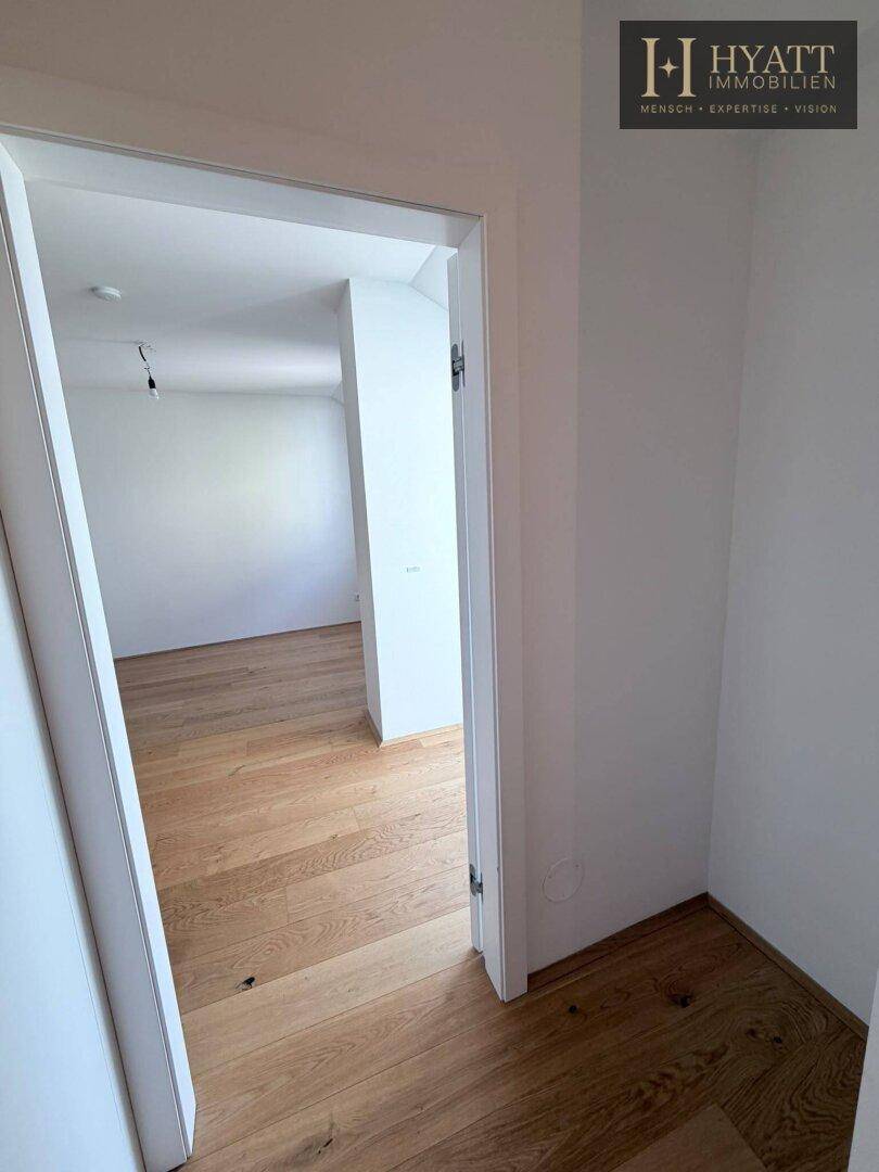 Heller Durchgangsbereich mit Holzboden, der den Blick in einen weiteren Raum freigibt.