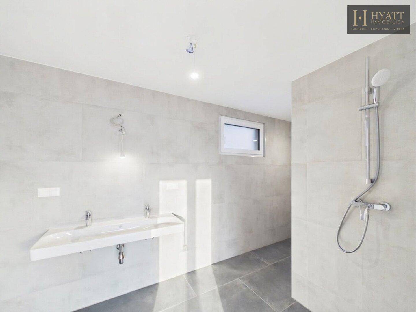 Modernes Badezimmer mit großformatigen Fliesen, Doppelwaschbecken und begehbarer Dusche.