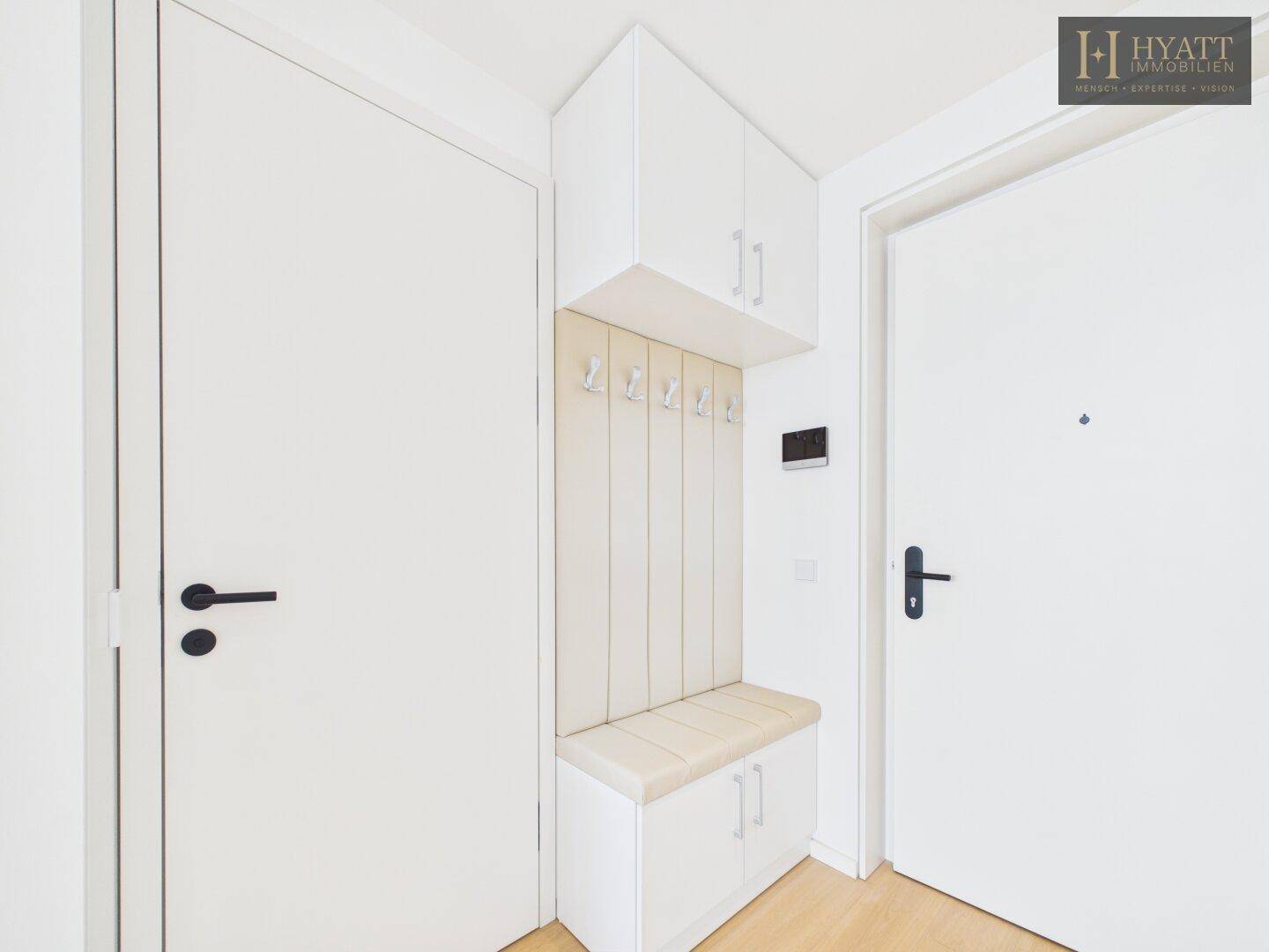 Eingangsbereich mit praktischer Garderobe, Sitzbank und integrierten Schränken in hellem Design.