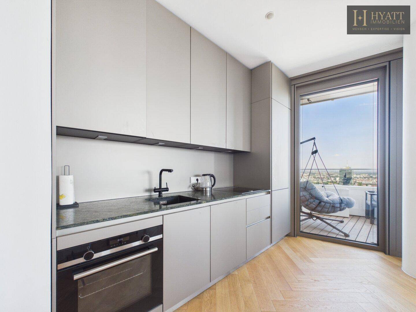 Kompakte, moderne Küchenzeile mit integrierten Geräten und Zugang zum Balkon.