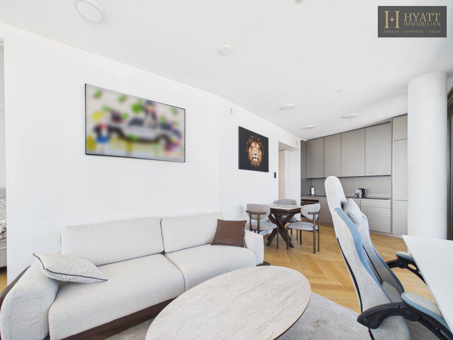 Gemütlicher Wohnbereich mit hellem Sofa, Couchtisch und Blick zur modernen Küche.