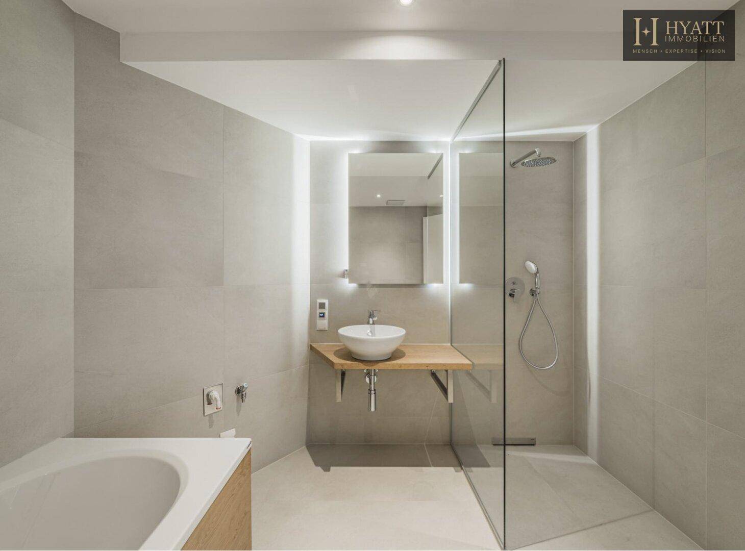 Modernes Badezimmer mit begehbarer Dusche, Glasabtrennung, Einzelwaschbecken und hellen Fliesen.