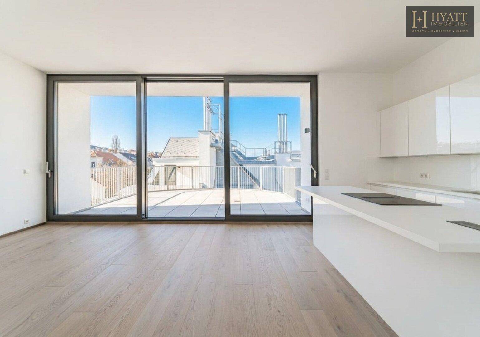 Lichtdurchfluteter Wohnbereich mit offener Küche, Holzboden und direktem Zugang zur großen Terrasse.